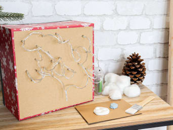 Christmas crafting with kids: LED fairy lights are attached to the cardboard box. Christmas crafting with kids: LED fairy lights are attached to the cardboard box.