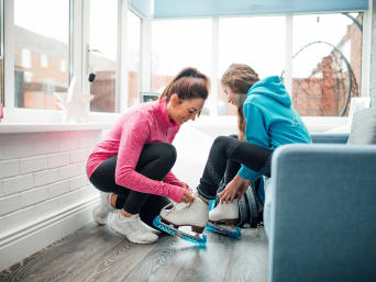 Eiskunstlauf Probetraining: Trainerin hilft Schülerin dabei, die Schlittschuhe anzuziehen. Eiskunstlauf Probetraining: Trainerin hilft Schülerin dabei, die Schlittschuhe anzuziehen.