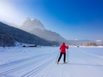 Langlauf Schweiz: Langläuferin fährt durch den Schnee und blickt auf die Zugspitze. Langlauf Schweiz: Langläuferin fährt durch den Schnee und blickt auf die Zugspitze.