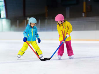 Eishockey spielen lernen: Zwei Kinder üben Eishockey in einer Eishalle. Eishockey spielen lernen: Zwei Kinder üben Eishockey in einer Eishalle.