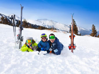 Skifahren Regeln: Familie liegt im Schnee und lacht in die Kamera. Skifahren Regeln: Familie liegt im Schnee und lacht in die Kamera.