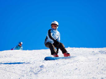 Snowboard Kinder: Junges Mädchen fährt auf ihrem Snowboard einen Hang herunter. Snowboard Kinder: Junges Mädchen fährt auf ihrem Snowboard einen Hang herunter.