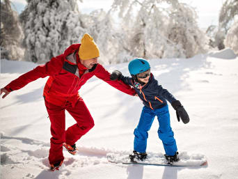 Leren snowboarden: snowboardleraar leert een kind snowboarden. Leren snowboarden: snowboardleraar leert een kind snowboarden.