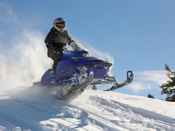 Trendsportart Winter: Ein Schneemobil fährt einen Hang herunter. Trendsportart Winter: Ein Schneemobil fährt einen Hang herunter.
