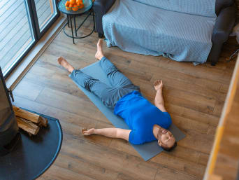 Yogapose Savasana – Man ligt op een yogamatje. Yogapose Savasana – Man ligt op een yogamatje.