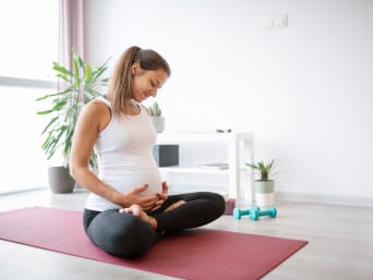 Pregnant Yoga - woman sitting in yoga position on the mat. Pregnant Yoga - woman sitting in yoga position on the mat.