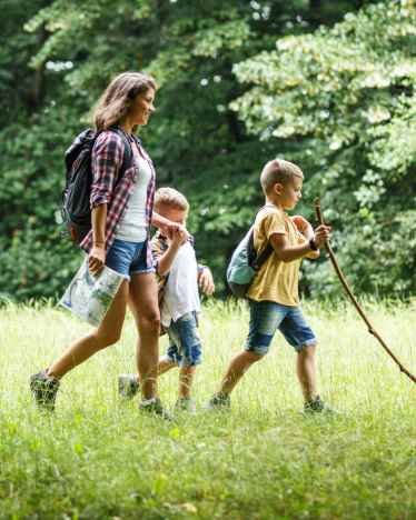 Gids natuurbeleving – Moeder loopt met haar kinderen door het bos.  Gids natuurbeleving – Moeder loopt met haar kinderen door het bos.