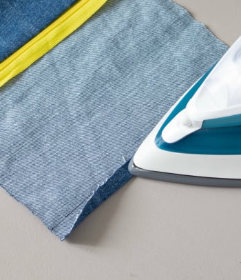 Upcycling a pair of jeans: ironing over the seam allowance.
